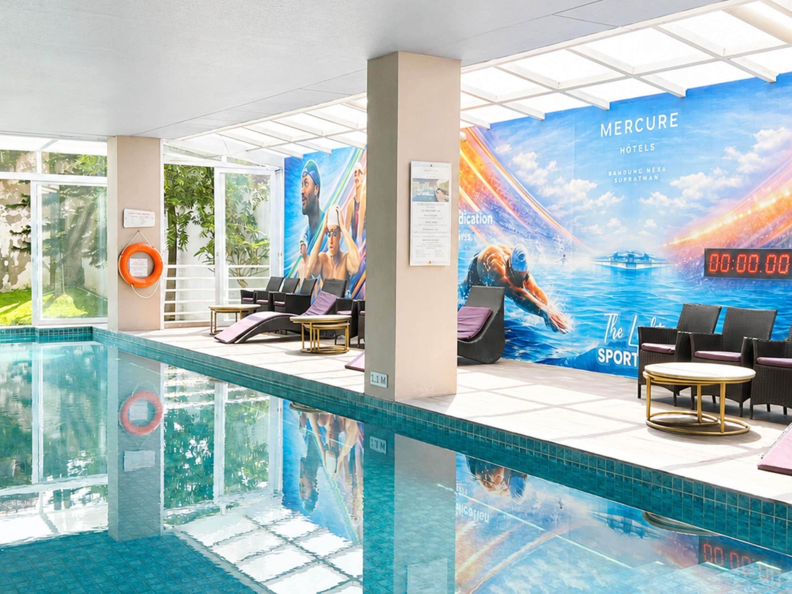 Zona de piscina con sillones reclinables, un flotador salvavidas y un mural grande que anuncia un hotel.