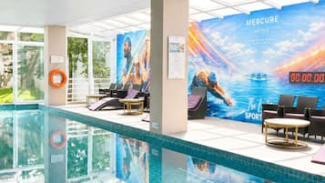 Zona de piscina con sillones reclinables, un flotador salvavidas y un mural grande que anuncia un hotel.
