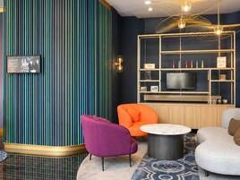 A modern living room with a striped wall, a television, and a seating area with a round coffee table.
