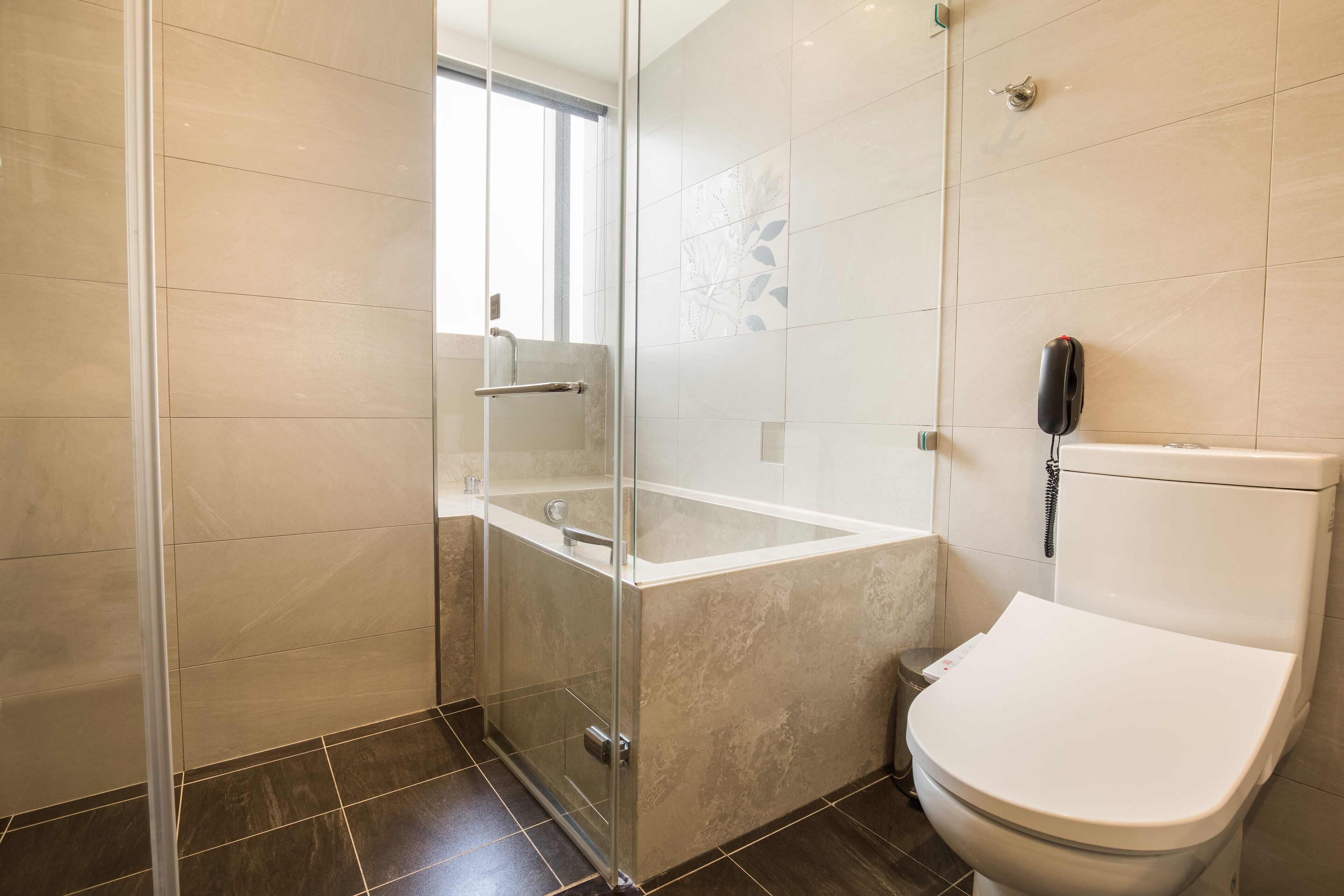 A modern bathroom with a glass-enclosed shower, a bathtub, and a toilet.