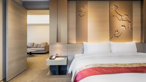 Una camera d'albergo moderna con un letto grande, un comodino con il telefono, un divano e un pannello decorativo a parete.