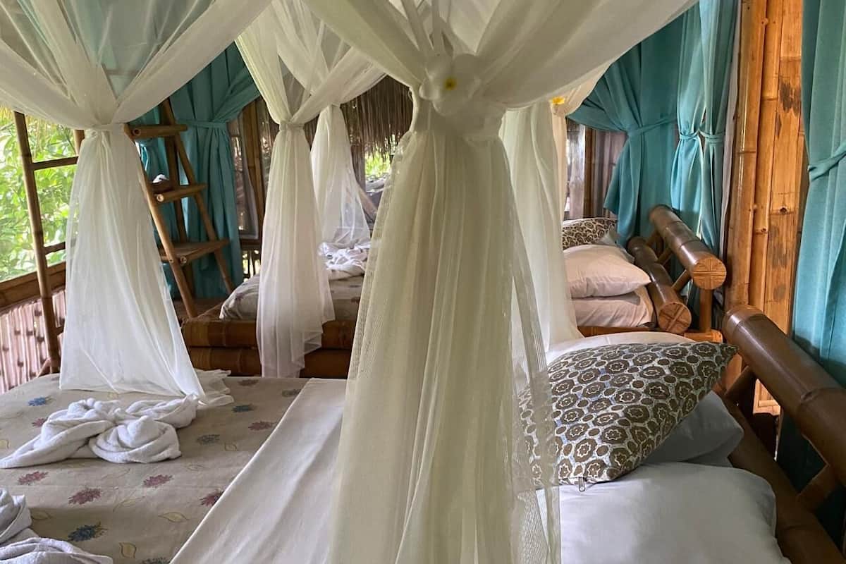 Une chambre dotée d’un lit à baldaquin, d’une tête de lit en bois et offrant une vue sur l’extérieur.