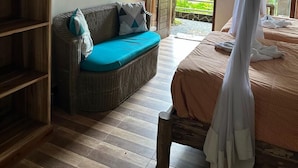 Een kamer met een bed, een bank, een houten boekenkast en een raam met uitzicht op groen.
