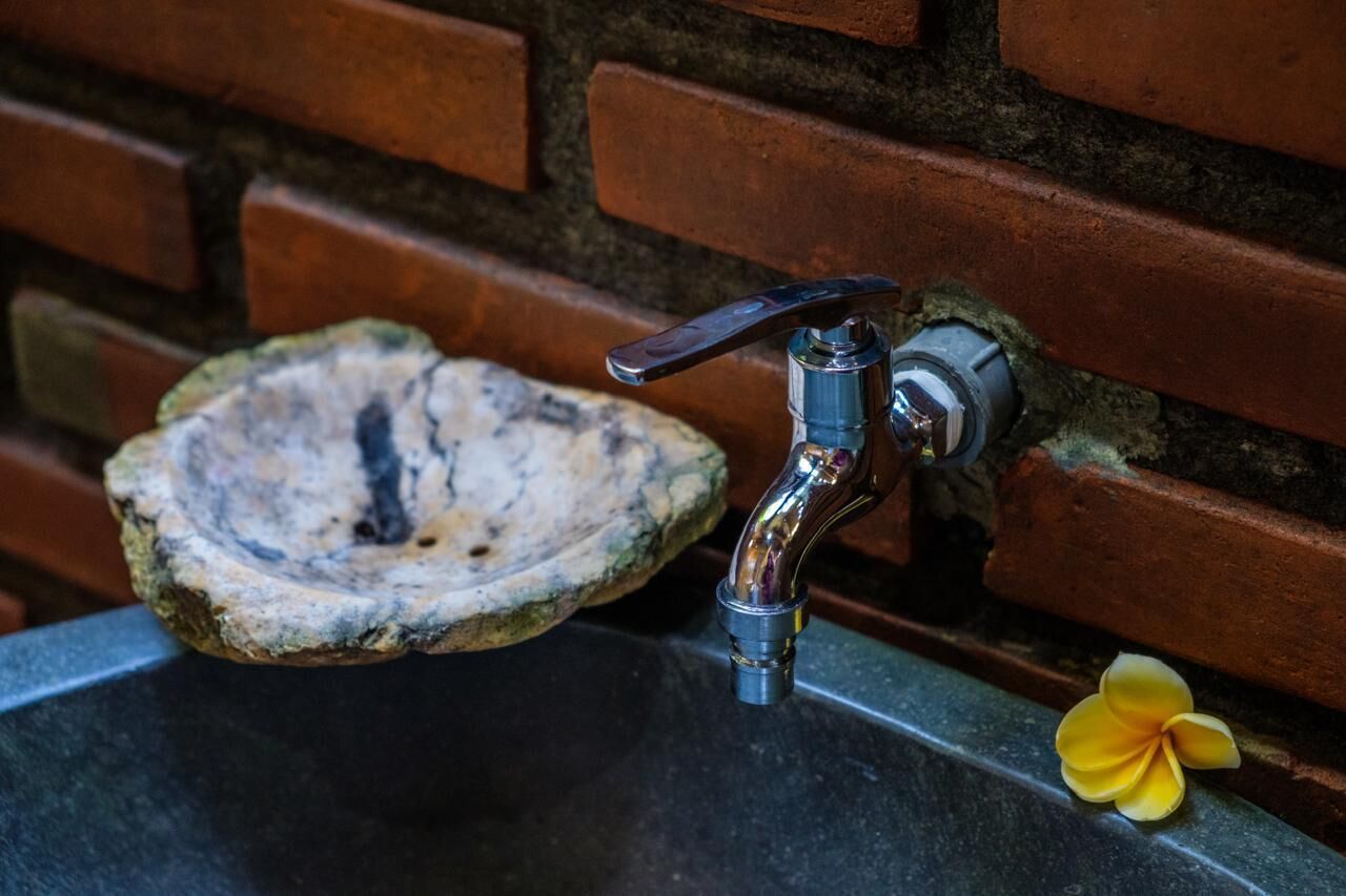 A sink with a faucet, a brick wall, and an oyster shell.