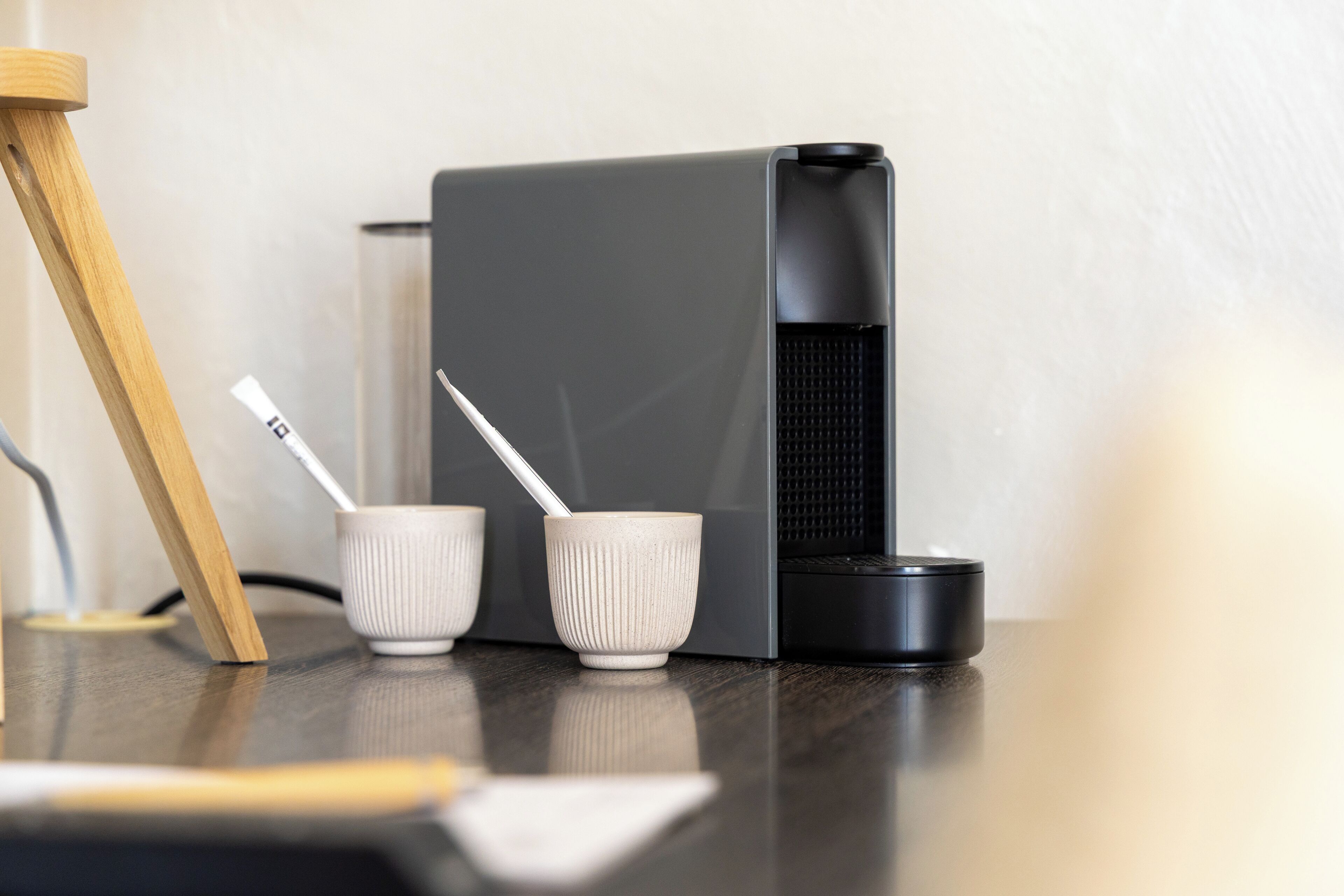 Una cucina moderna con una macchina da caffè, due tazze bianche e una sedia di legno.