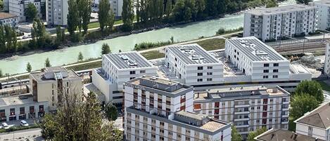 A modern hotel complex with multiple buildings, a river in the background, and a mix of residential and commercial structures nearby.