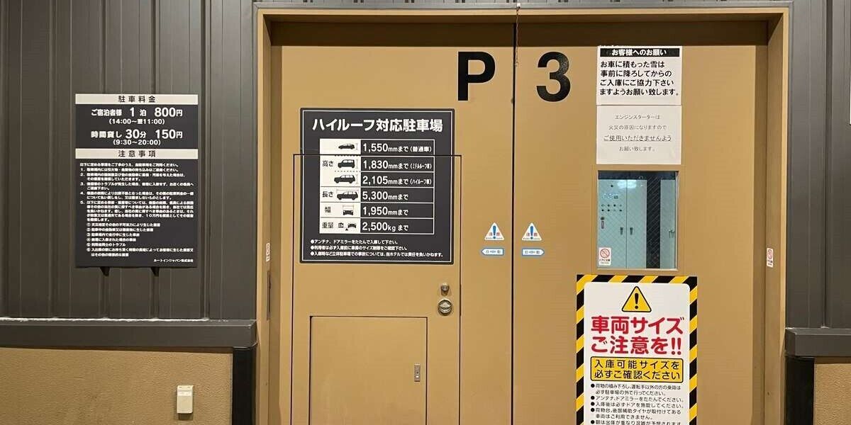 A hotel entrance with a sign indicating parking fees and a list of vehicle sizes allowed.