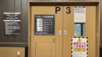 A hotel entrance with a sign indicating parking fees and a list of vehicle sizes allowed.