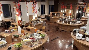 Un restaurante con varias zonas de comedor, mobiliario de madera y una variedad de platos expuestos en las mesas.