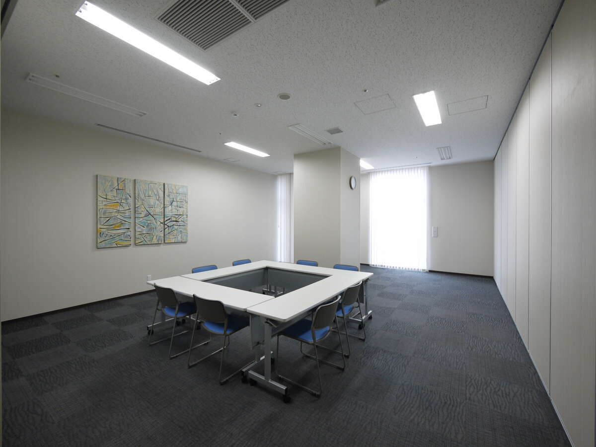 A conference room with a large table, chairs, and artwork on the walls.