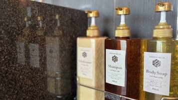 Drei Flaschen Dusch-Pausen-Shampoo, Badeseife und Shampoo auf einer Granit-Arbeitsplatte.