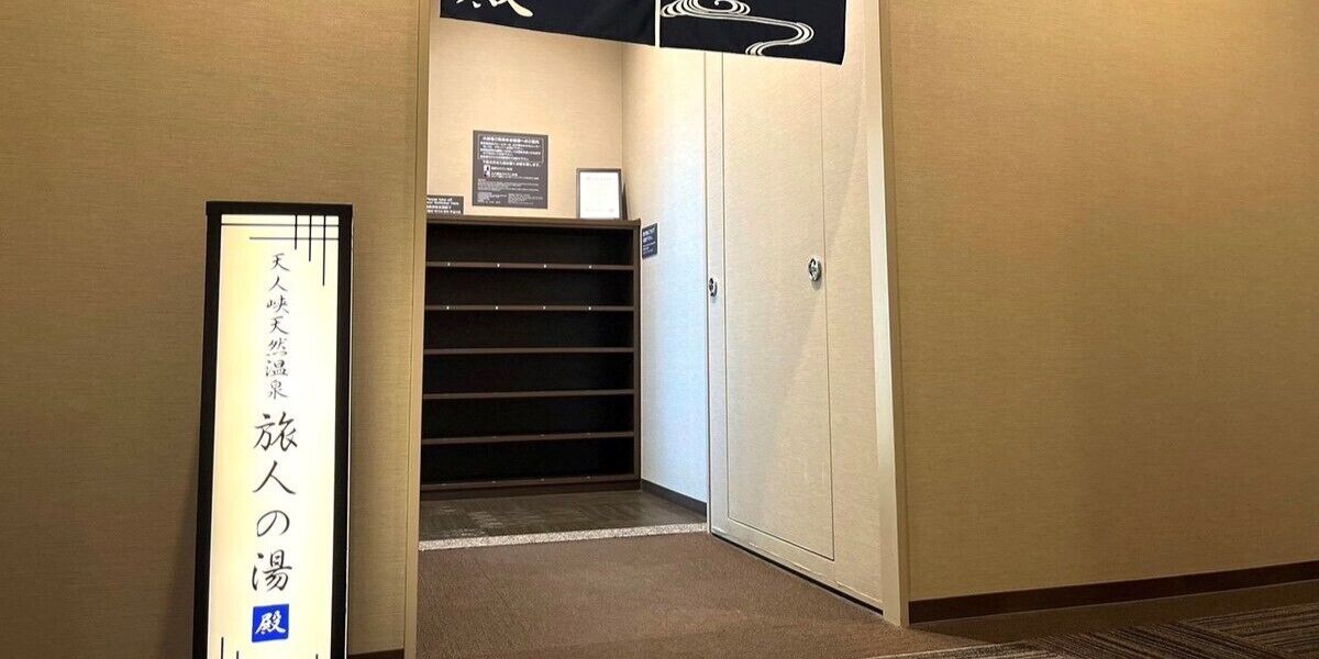 Um corredor com piso carpeteado, uma porta fechada e uma placa emoldurada na parede.