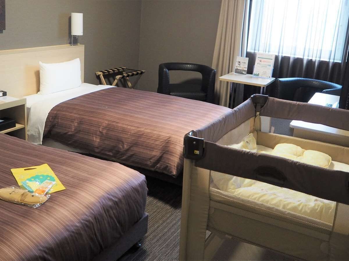 A hotel room with two beds, a desk, a chair, and a small table.