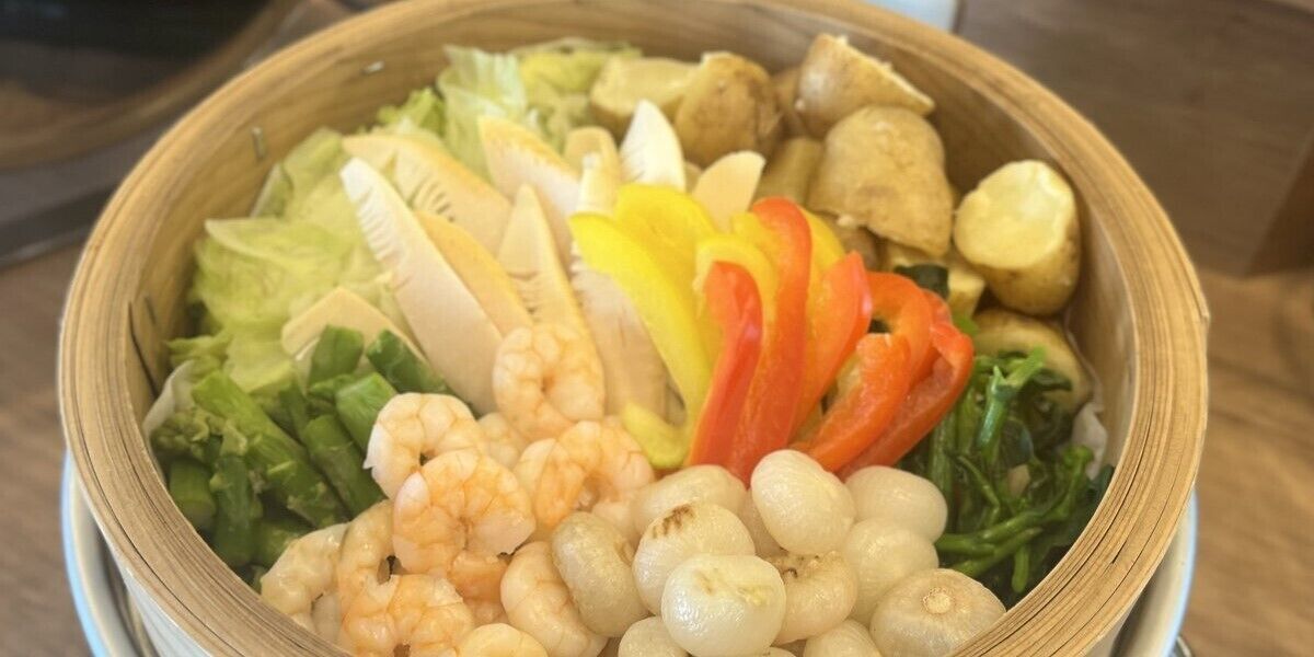 A wooden bowl containing various seafood and vegetables.