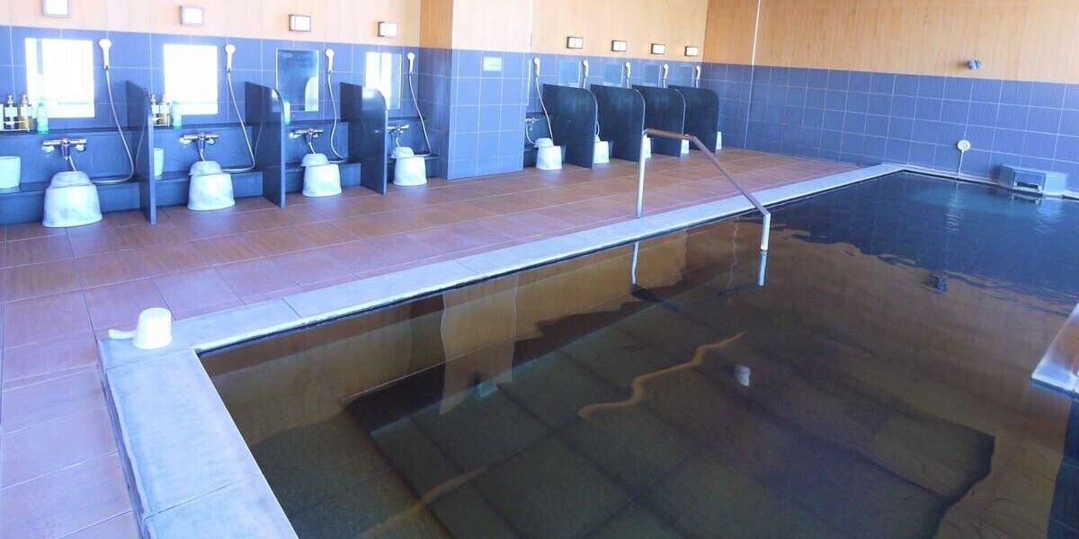 Una piscina con barrera de vidrio, varios vestuarios y suelo de baldosas.