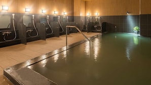 Piscina interior climatizada con múltiples duchas y una zona de estar central.