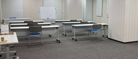 Une salle de classe équipée de plusieurs bureaux, de chaises et d’un tableau blanc.