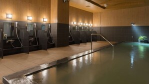 Un área de piscina interior moderna con múltiples duchas y una piscina central.
