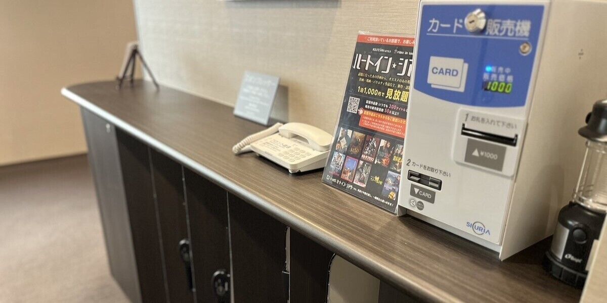 A reception desk with a phone, a card reader, and a poster.