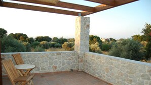 A stone-walled balcony with a wooden pergola, two wooden chairs, and a view of a green landscape. - Pyrgos Luxury Country Home (Rhodes)