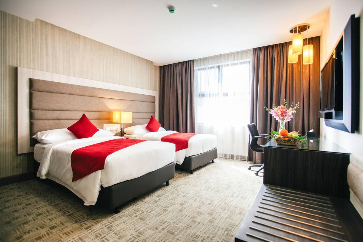 Ein Hotelzimmer mit zwei Betten, einem Schreibtisch und einem Stuhl.