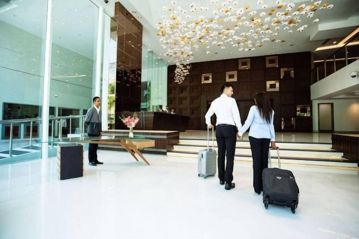 Eine moderne Lobby mit einer Rezeption, einer Treppe und einem Glasgeländer.
