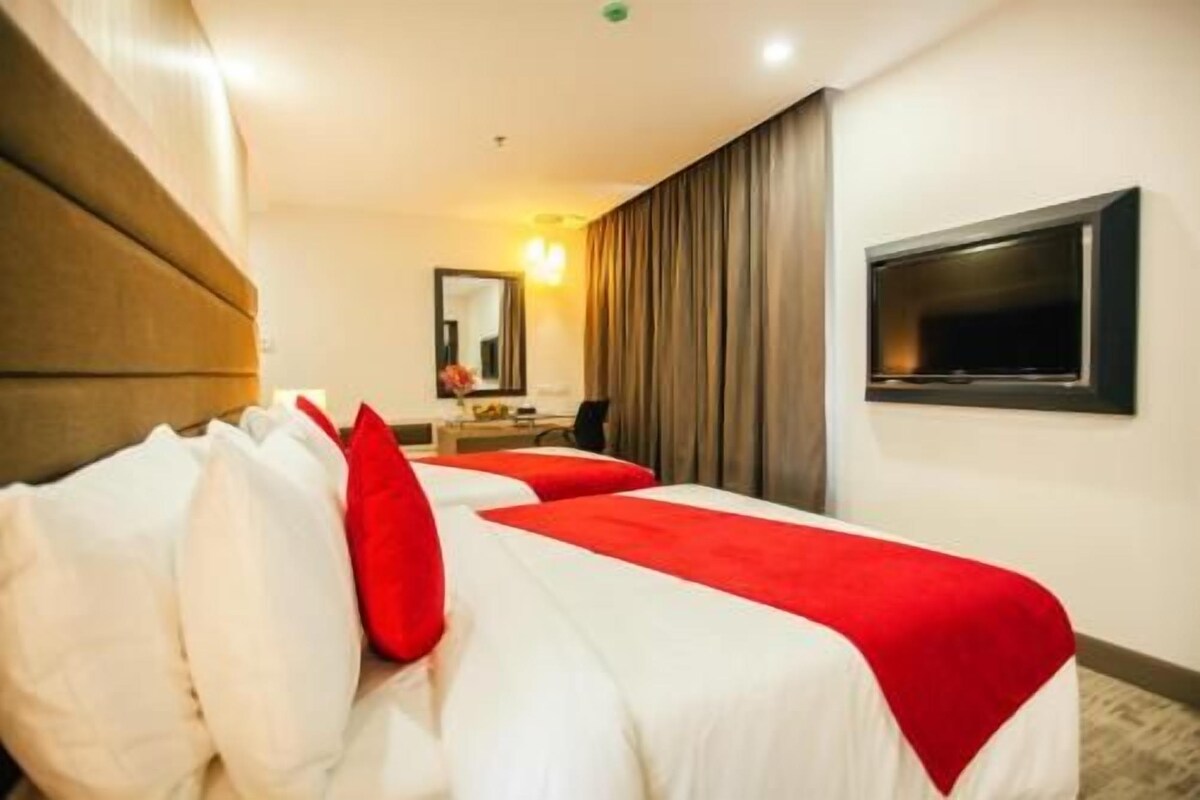 Een hotelkamer met twee bedden, een televisie, een bureau en een spiegel.