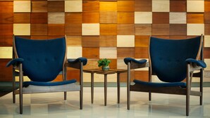 Two blue chairs and a small table with a plant in a room with a checkered wooden wall. - Verdant Hill Hotel Kuala Lumpur (Kuala Lumpur)