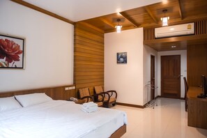 A hotel room with a bed, a chair, a desk, and an air conditioning unit. - Tree Home Plus Home Stay (Nakhon Si Thammarat)