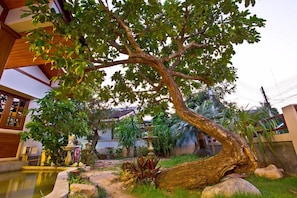 A tree in a courtyard with a fountain and potted plants. - Tree Home Plus Home Stay (Nakhon Si Thammarat)