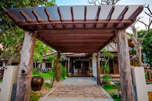A wooden pergola structure with a brick pathway leading to a building. - Tree Home Plus Home Stay (Nakhon Si Thammarat)