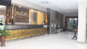 A hotel reception area with a modern design, a reception desk, and a potted plant. - Horison Kota Lama Semarang (Semarang)