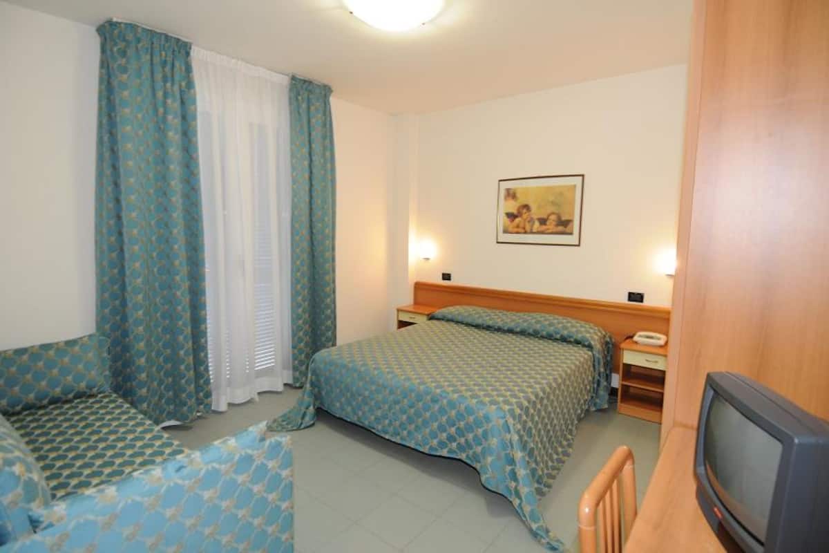 A hotel room with two beds, a television, and a painting on the wall.