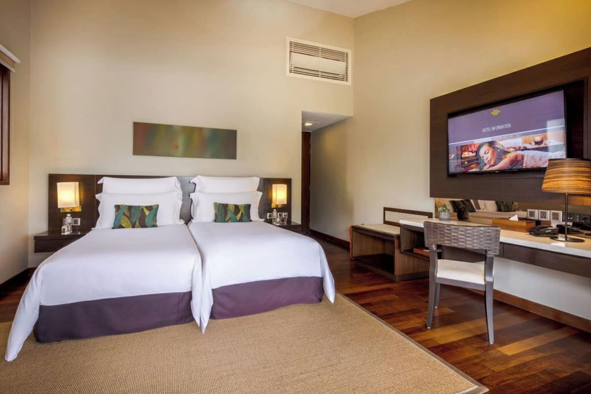 A hotel room with a large bed, a desk, a chair, a TV, and a painting on the wall.