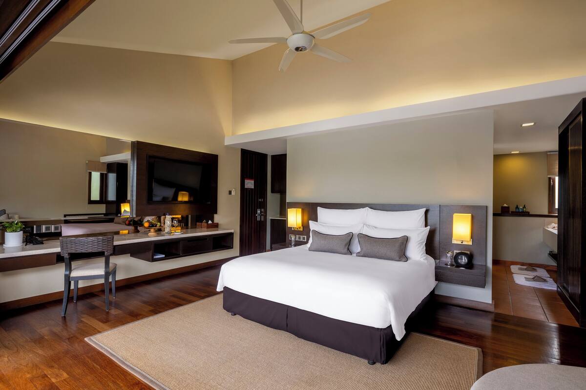 Una habitación de hotel moderna con una cama grande, un escritorio y un televisor.