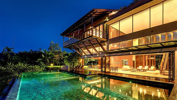 Une maison moderne à deux étages dotée d’une piscine, d’un espace salon extérieur et d’un balcon.