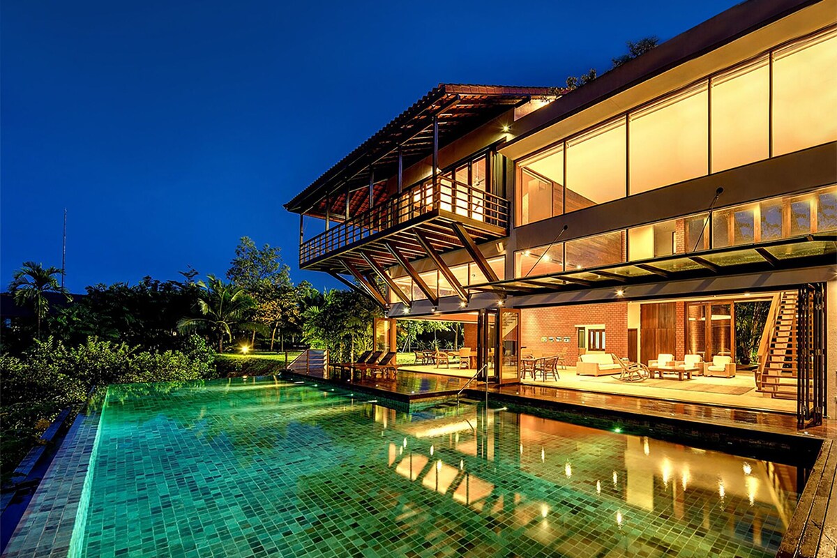 Uma casa moderna de dois andares, com piscina, área de estar externa e varanda.