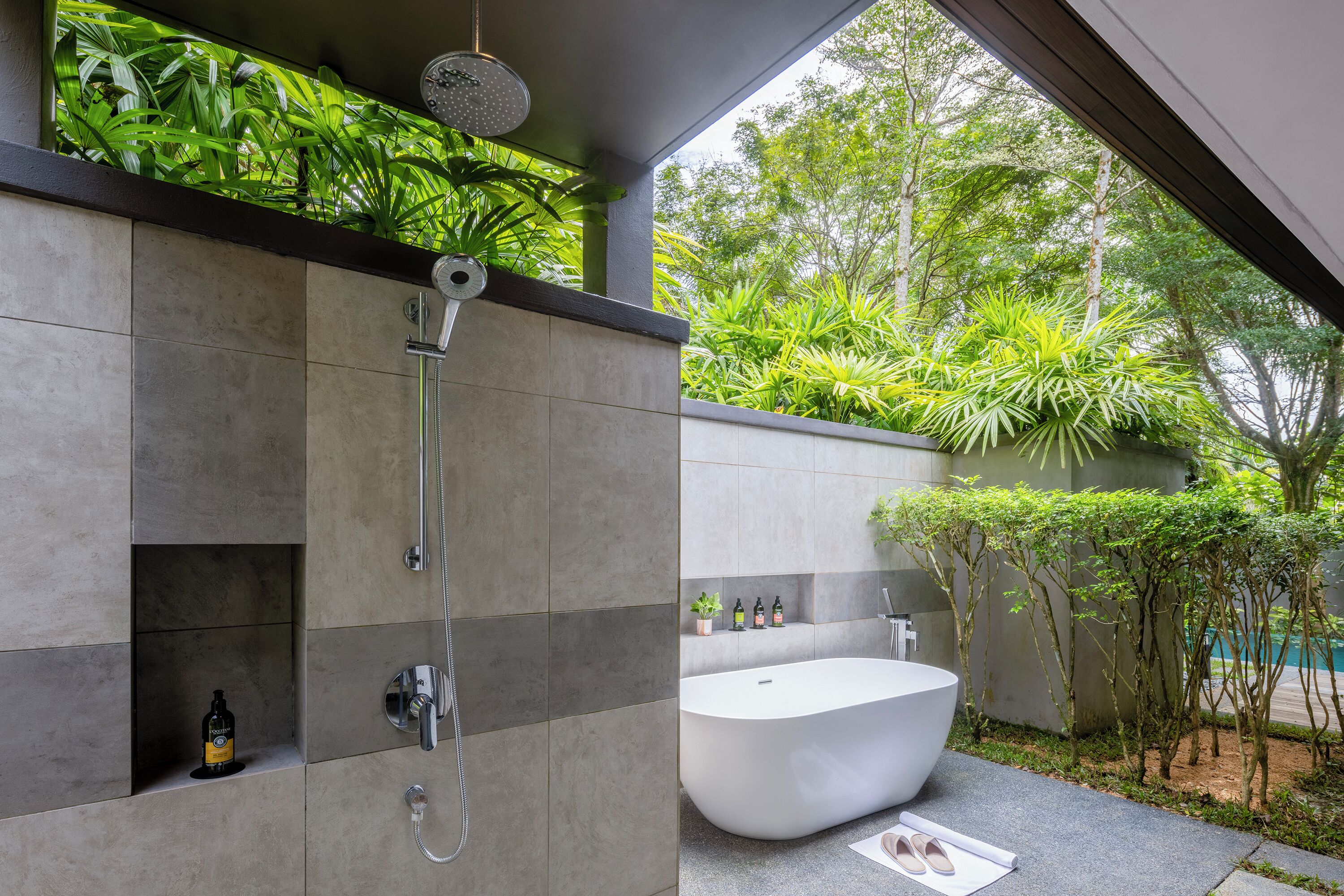 A modern bathroom with a freestanding bathtub, a shower, and a shelf with toiletries.