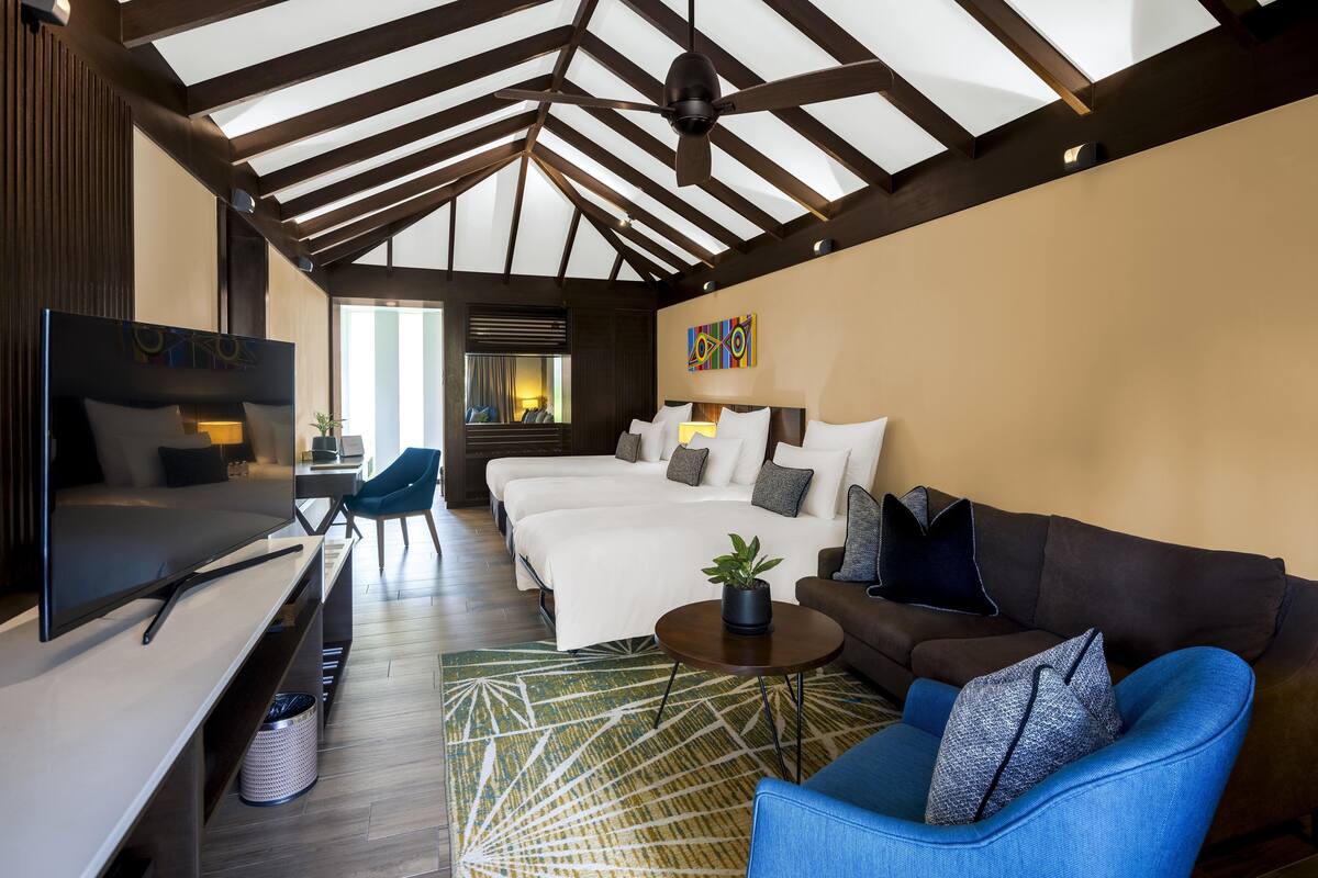 Una habitación de hotel moderna con una cama grande, un sofá, un televisor y un escritorio.