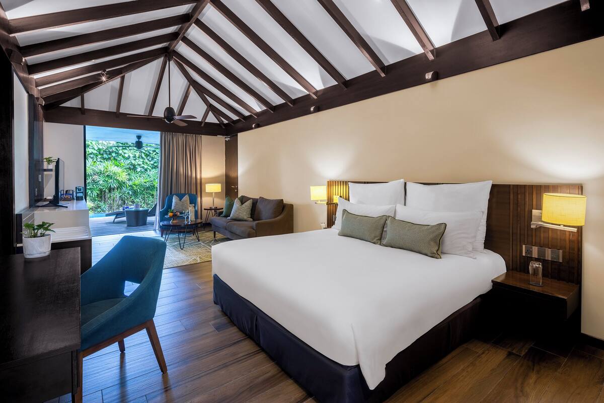Habitación de hotel con una cama grande, un escritorio, una silla y vistas a zonas verdes.