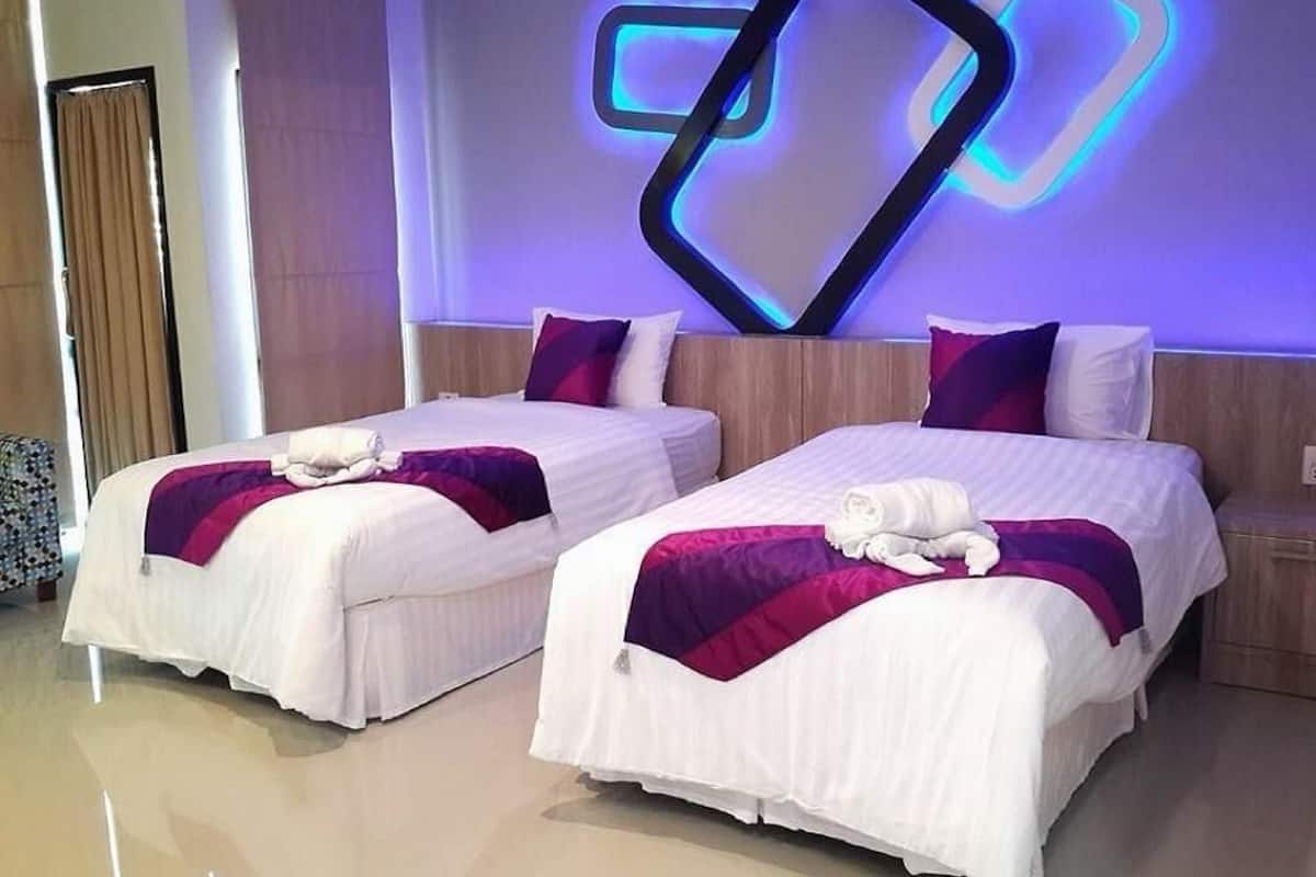 Two twin beds with white and purple bedding, a modern wall art piece, and a wooden headboard.