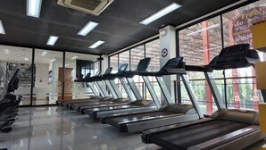 Un gimnasio con varias cintas de correr, amplias ventanas y un diseño moderno y limpio.