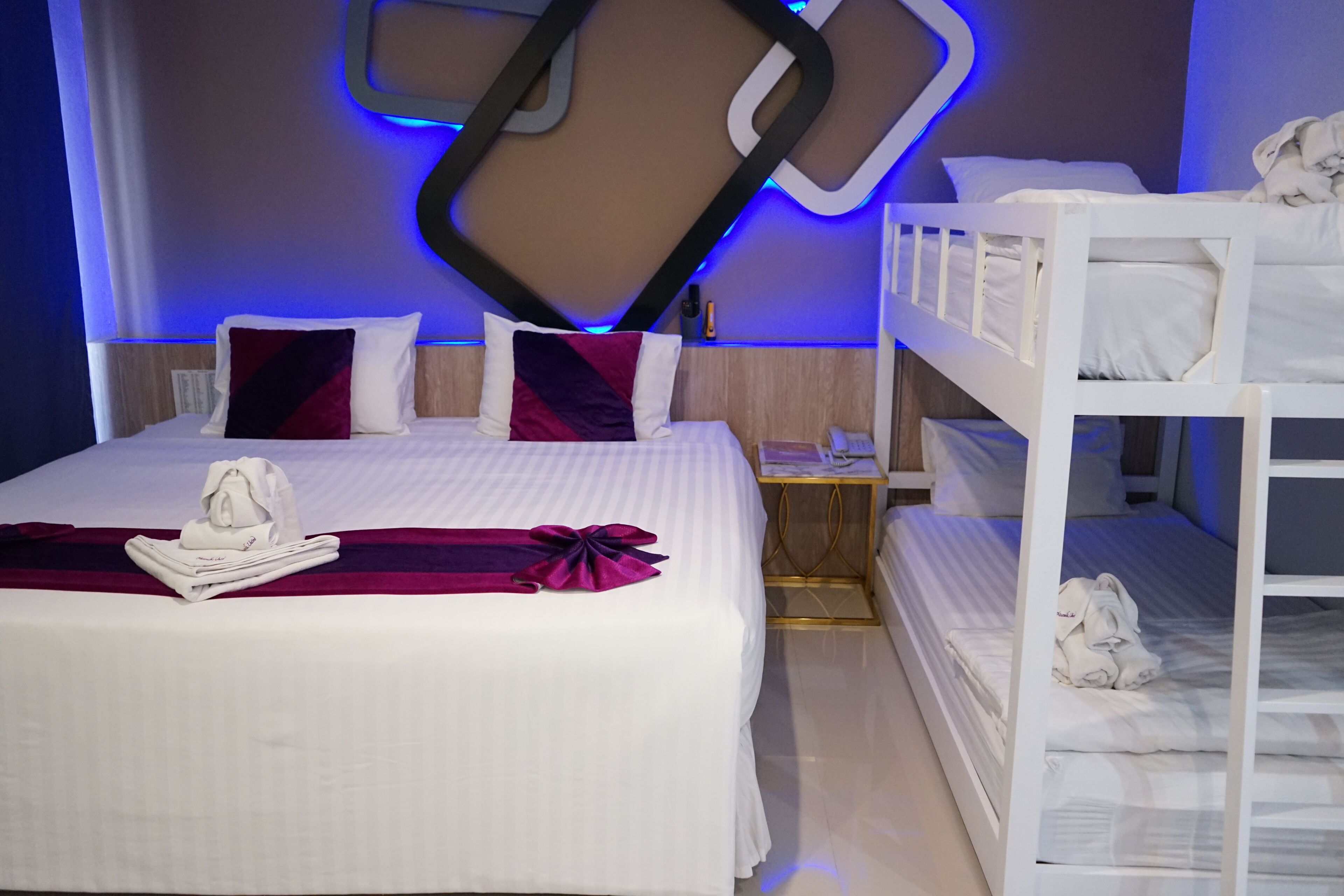 A hotel room with a large bed, a bunk bed, and a desk with a phone.