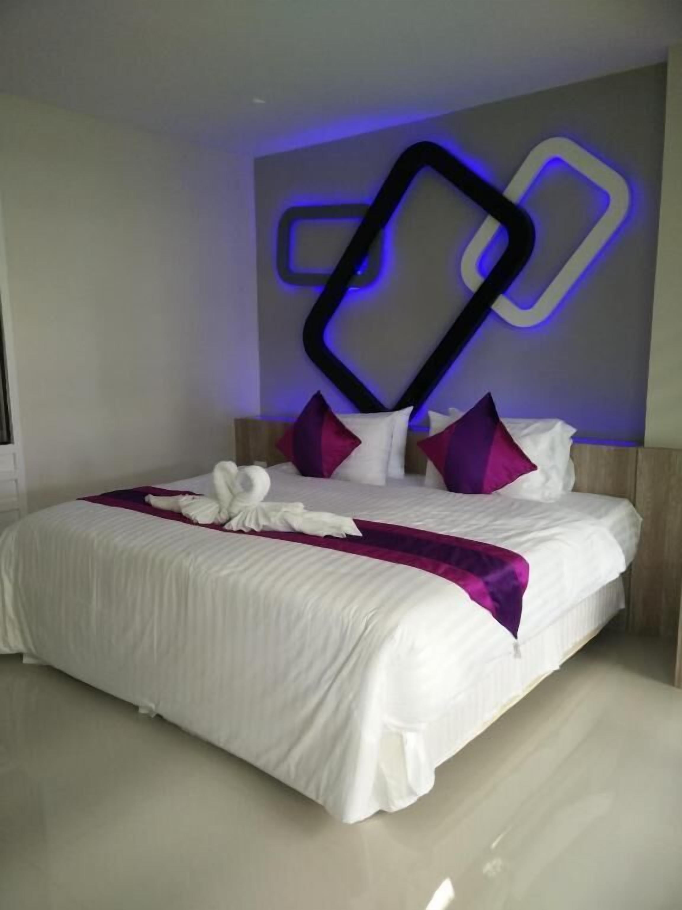 A modern hotel room with a neatly made bed, a decorative wall piece, and a clean, minimalist design.