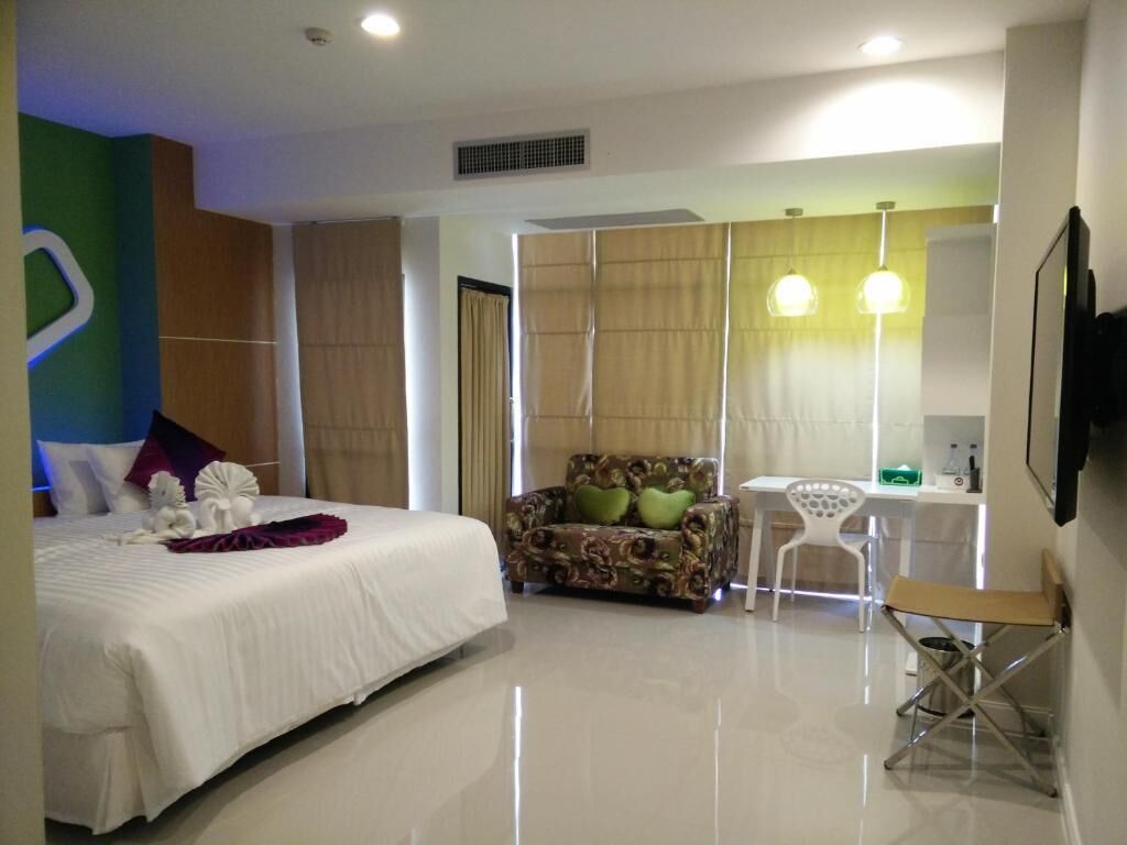 A modern hotel room with a large bed, a sofa, a small table, and a chair.