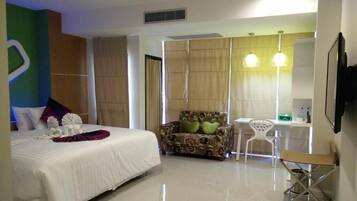 A modern hotel room with a large bed, a sofa, a small table, and a chair.
