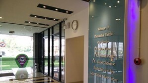 Un moderno vestíbulo de hotel con un muro de cristal que muestra servicios como gimnasio, spa y café.