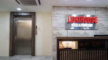 An elevator and a reception desk with a sign for Lighthouse Hotel & ShortStay.
