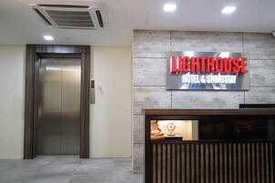 An elevator and a reception desk with a sign for Lighthouse Hotel & ShortStay.