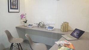 Un mostrador de recepción con una computadora portátil, un reloj y una planta en maceta.